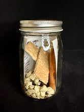 Load image into Gallery viewer, Mason jar with cinnamon sticks, dried apples, graham cracker, and brown sugar fig cube on a black background
